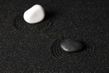 Arka plan olarak siyah kumdaki taşlar. Yin Yang konsepti