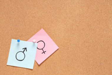 Arka plan olarak mantar panoda kadın ve erkek cinsiyet sembolleri olan çıkartmalar