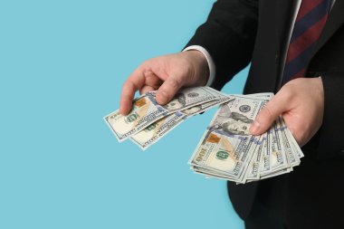 İşadamı mavi arkaplanda dolar banknotları sayıyor, yakın plan.
