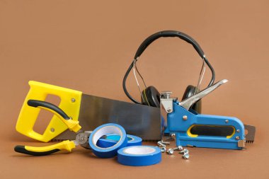 Kahverengi arka planda marangoz aletleri ve işitme koruma kulaklıkları