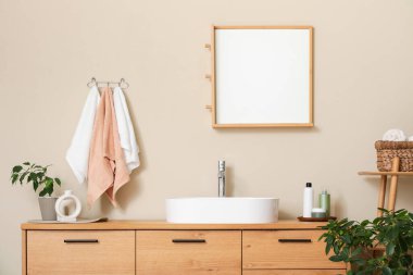 Modern lavabonun yanındaki bej duvarda asılı temiz havlular.