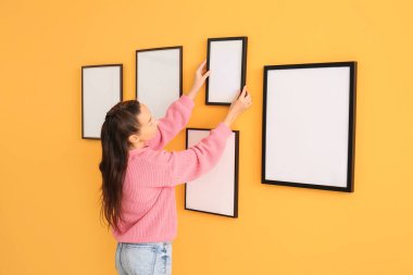 Odadaki duvara boş fotoğraf çerçeveleri asan kadın.