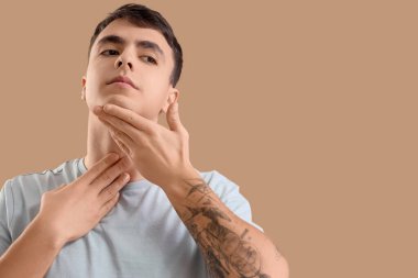 Genç adam bej arka plan üzerinde yüz geliştirme egzersizi yapıyor.