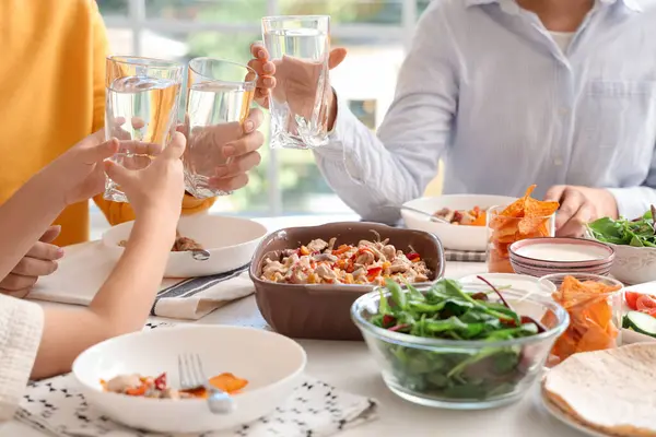 Küçük çocuk ve ailesi bir bardak suyla mutfakta Fajita yiyorlar, yakın plan.