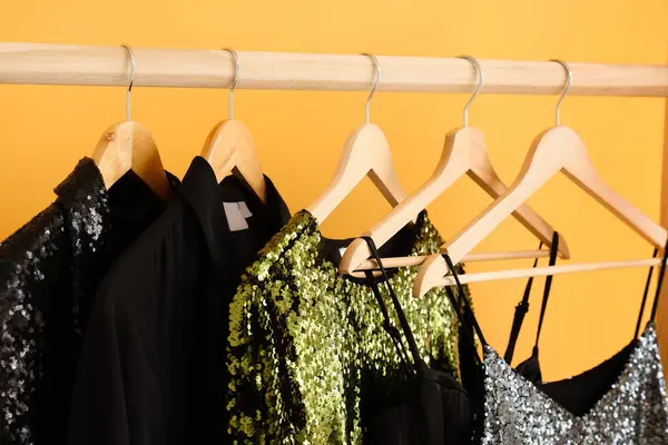 Soyunma odasındaki sarı duvarın yanında gece elbiseleriyle dizilin. Yakın çekim.