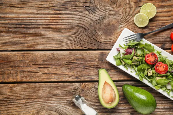 Çeri domatesli lezzetli avokado salatası ve ahşap arka planda limon dilimleri.