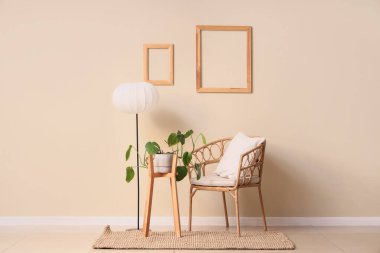 Hasır koltuklu, lambalı ve bej duvarlı bir ev bitkisi.