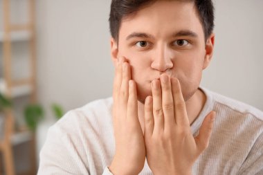 Genç adam tuvalette yüz geliştirme egzersizi yapıyor.