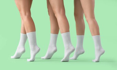 Yeşil arka planda şık beyaz çoraplı genç kadınların bacakları