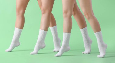 Yeşil arka planda şık beyaz çoraplı genç kadınların bacakları
