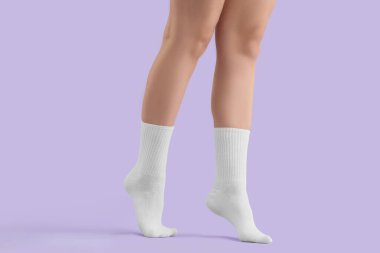 Leylak arkaplanda beyaz çoraplı genç bir kadının bacakları.