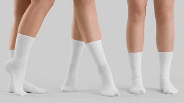 Gri arka planda şık beyaz çoraplı genç kadınların bacakları