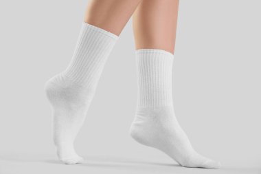 Gri arka planda şık beyaz çoraplı genç kadın bacakları