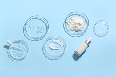 Mavi arka planda numune ve bir şişe kozmetik ürünü içeren petri kapları