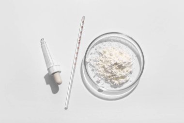 Beyaz zemin üzerinde barut örneği, profesyonel cam eşyalar ve pipetle Petri kabı.