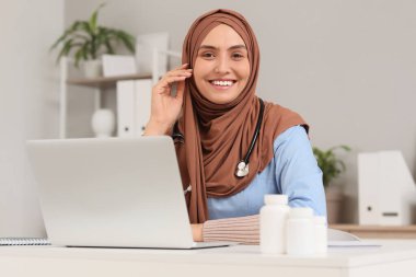 Klinikteki masada gülümseyen Müslüman kadın doktor