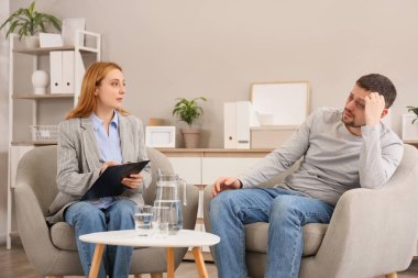 Ofisteki koltuklarda uyuşturucu bağımlısıyla çalışan kadın psikolog.