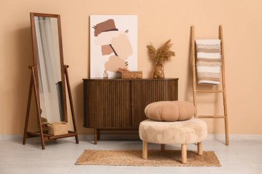 Oturma odasının içinde ayna, puf ve ev dekoru kahverengi duvarın yanında.