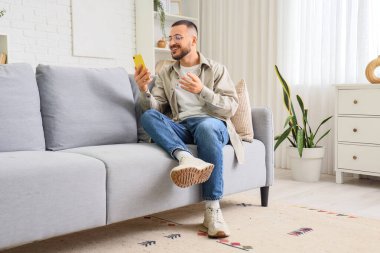 Genç adam evde kız arkadaşıyla sohbet etmek için cep telefonunu kullanıyor. Online randevu