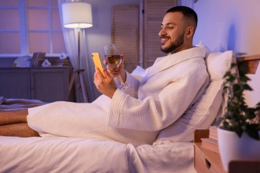 Genç adam şarap içiyor ve akşam kız arkadaşıyla görüntülü sohbet ediyor. Online randevu