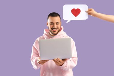 Diz üstü bilgisayarı olan ve eflatun arkaplanda konuşma balonu tutan genç bir adam. Online randevu