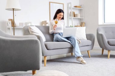 Şarap içen ve evde erkek arkadaşıyla görüntülü sohbet eden genç bir kadın. Online randevu