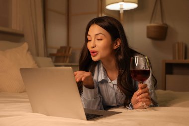 Şarap içen ve akşam erkek arkadaşıyla görüntülü sohbet eden genç bir kadın. Online randevu