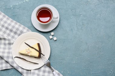 Bir parça vanilyalı cheesecake ve mavi arkaplanda bir fincan çay.