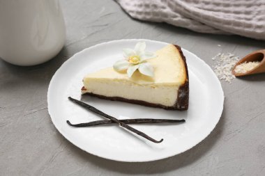 Gri arkaplanda bir parça vanilyalı cheesecake.