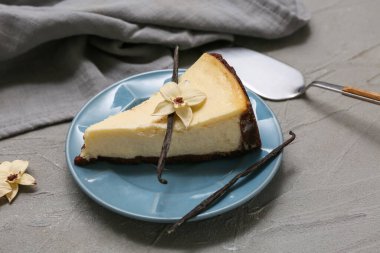 Gri arkaplanda bir parça vanilyalı cheesecake.