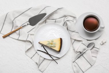 Bir parça vanilyalı peynirli kek ve beyaz arka planda bir fincan çay.