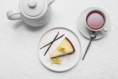 Bir parça vanilyalı peynirli kek ve beyaz arka planda bir fincan çay.