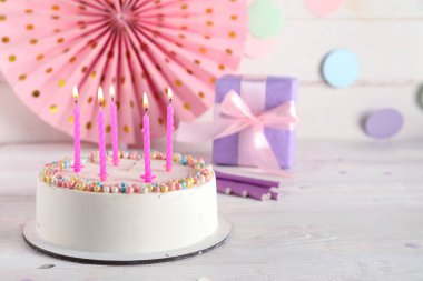 Güzel doğum günü pastası yanan mumlar, hediye kutusu ve açık ahşap masa üzerindeki dekor.