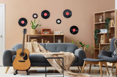 Oturma odasının içinde gitar, vinil diskler ve kanepe var.