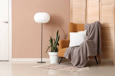 Koltuk, lamba ve katlanan ekran kahverengi duvarın yanında.