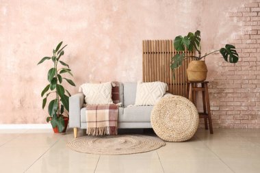 Oturma odasının iç tarafında rahat bir kanepe, puf ve bitkiler var.