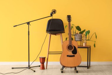 Sarı duvarın yanında müzik aletleri olan tabure ve masa.