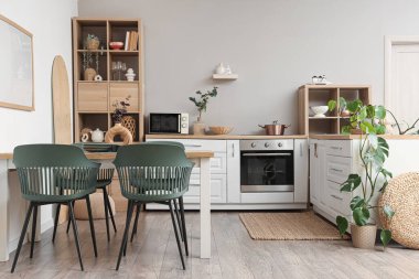 Mutfağın içinde yemek masası, tezgah ve raf üniteleri var.