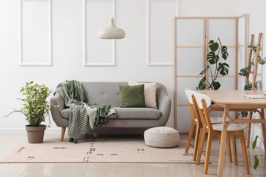 Yemek masası, katlanır ekran ve kanepesi olan ışık odasının içinde.