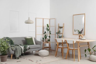 Yemek masası, katlanır ekran ve kanepesi olan ışık odasının içinde.