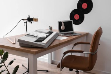 Stüdyoda sentezleyici, dizüstü bilgisayar ve mikrofonlu müzisyen işyeri