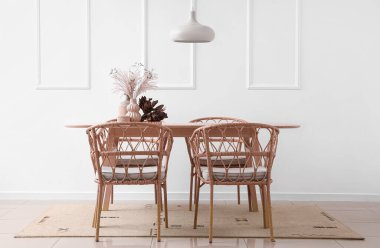 Aydınlık odada, yemek masasının üstünde kurumuş çiçekli vazolar.