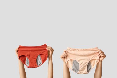 Gri arka planda farklı dönemden kalma külotlu kadın elleri