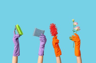 Lastik eldivenli, süngerli ve mavi arka planda çiçekli kadın elleri.