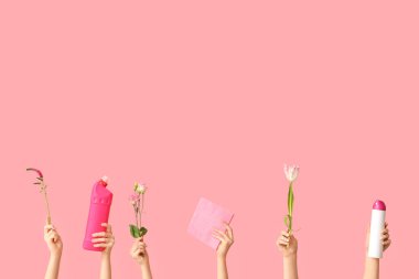 Pembe arka planda deterjan, paçavra ve çiçeklerle dolu bir sürü kadın eli