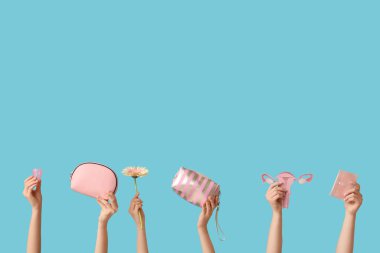 Adet bardağı, kozmetik poşet, ped ve mavi arka planda kağıt rahim olan kadın elleri.