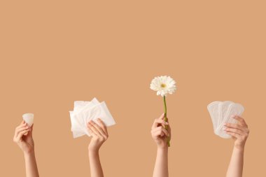 Regl fincanı, pedleri ve bej arkaplanda çiçekli kadın elleri