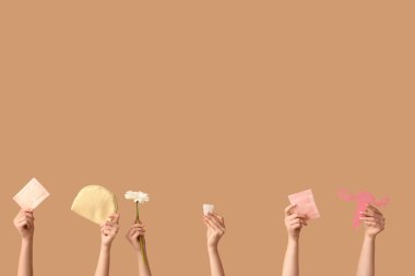 Regl pedi, kozmetik poşet ve bej arka planda kağıt rahim olan birçok kadın eli.