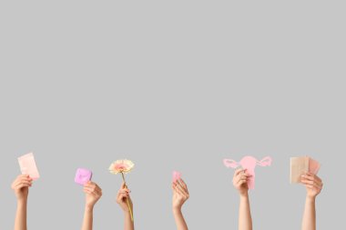 Regl pedleri, kağıt uterusu ve gri arka planda tampon saklama kutusu olan birçok kadın eli.