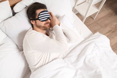 Uyku maskeli yakışıklı genç adam evde uyuyor.